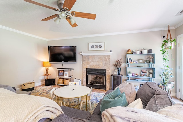 living room featuring a textured ceiling, ceiling fan, ornamental molding, and a fireplace