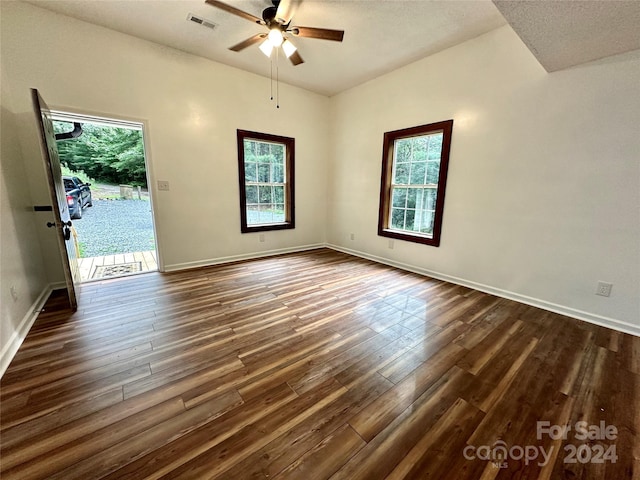 unfurnished room with ceiling fan, dark wood-type flooring, and plenty of natural light