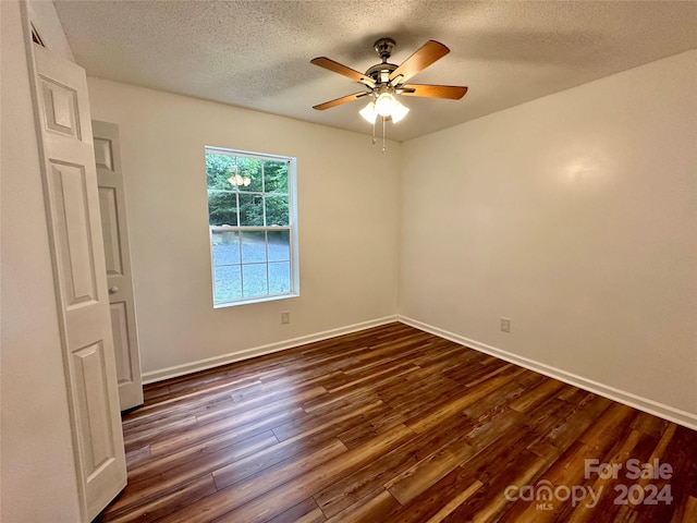 empty room featuring a textured ceiling, ceiling fan, and dark wood-type flooring