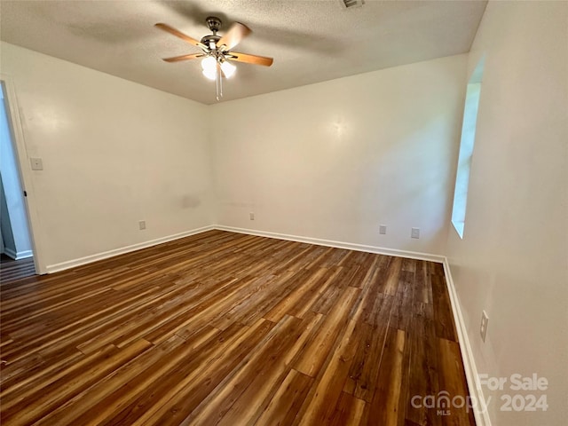 empty room with a textured ceiling, ceiling fan, and dark wood-type flooring