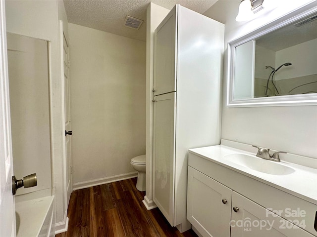 bathroom with toilet, hardwood / wood-style flooring, a textured ceiling, and vanity