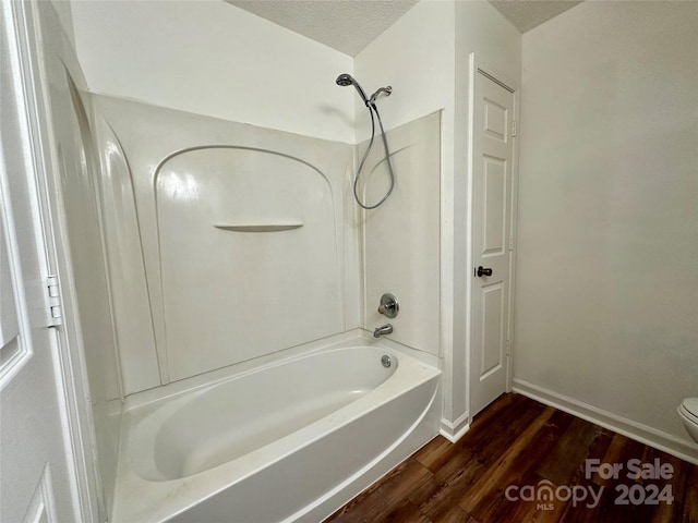 bathroom with toilet, wood-type flooring, a textured ceiling, and shower / tub combination