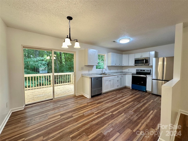 kitchen with stainless steel appliances, sink, white cabinetry, a chandelier, and pendant lighting