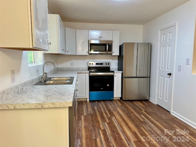 kitchen featuring a textured ceiling, dark hardwood / wood-style flooring, white cabinets, appliances with stainless steel finishes, and sink