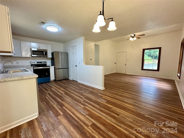 kitchen featuring appliances with stainless steel finishes, a textured ceiling, white cabinetry, decorative light fixtures, and sink