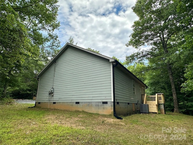 view of side of home with central AC unit and a lawn