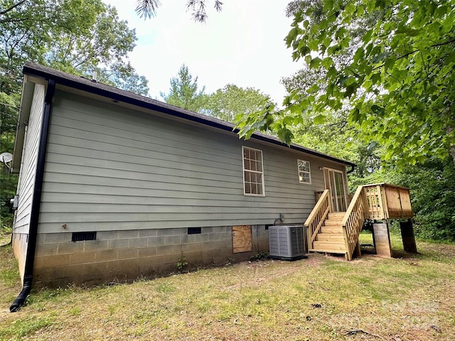 view of property exterior featuring a deck, central AC unit, and a lawn