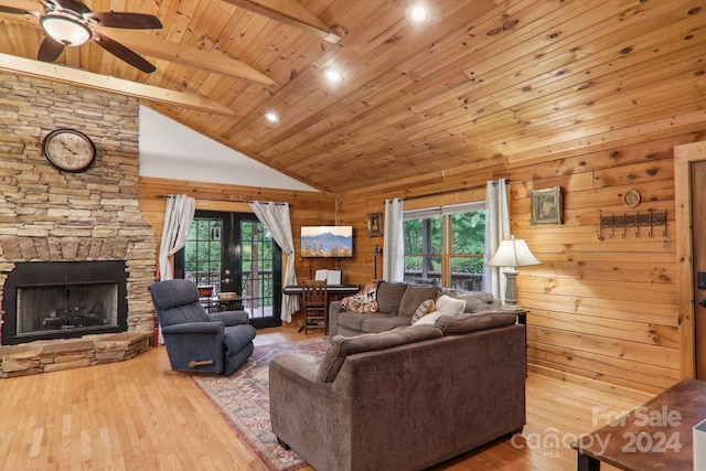 living room with wood walls, a stone fireplace, wooden ceiling, high vaulted ceiling, and beamed ceiling