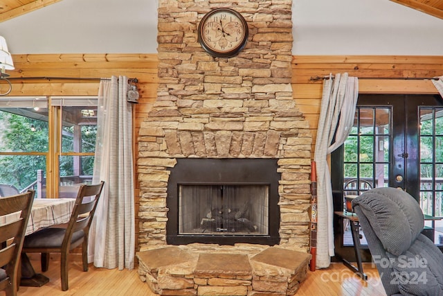 living room with lofted ceiling, a fireplace, wooden walls, and light hardwood / wood-style floors