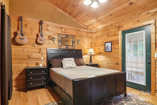 bedroom with lofted ceiling, wood ceiling, wooden walls, and light hardwood / wood-style floors