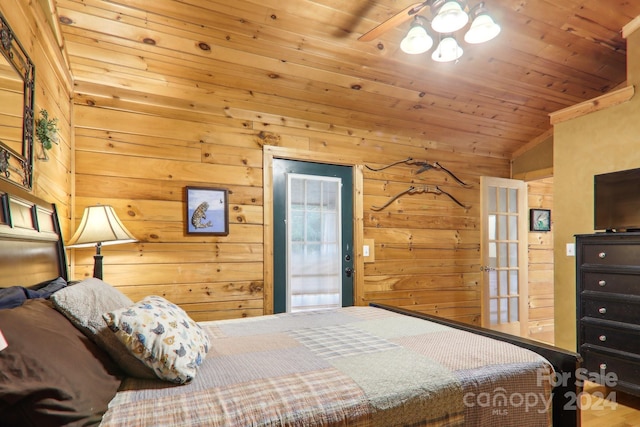 bedroom with vaulted ceiling, wooden ceiling, wood walls, and ceiling fan