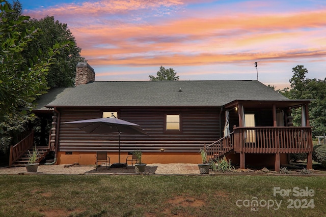 back house at dusk featuring a deck and a yard