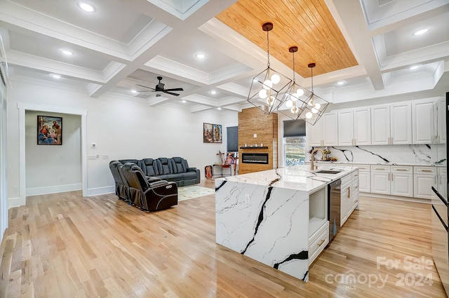 kitchen with white cabinets, light wood-type flooring, a center island with sink, and sink