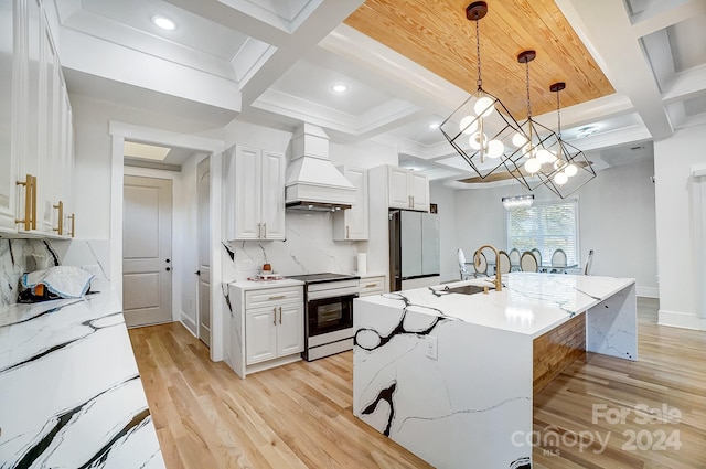 kitchen featuring appliances with stainless steel finishes, custom exhaust hood, a kitchen island with sink, white cabinets, and hanging light fixtures