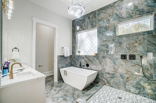 bathroom featuring vanity, an inviting chandelier, a bath, and tile walls