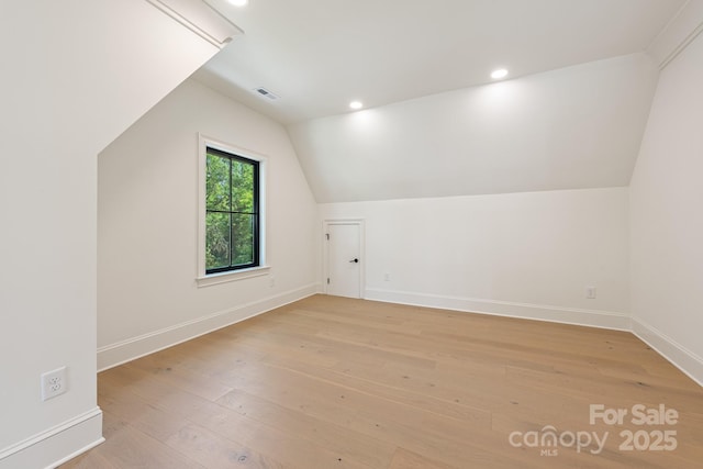 additional living space with light wood finished floors, recessed lighting, baseboards, vaulted ceiling, and visible vents