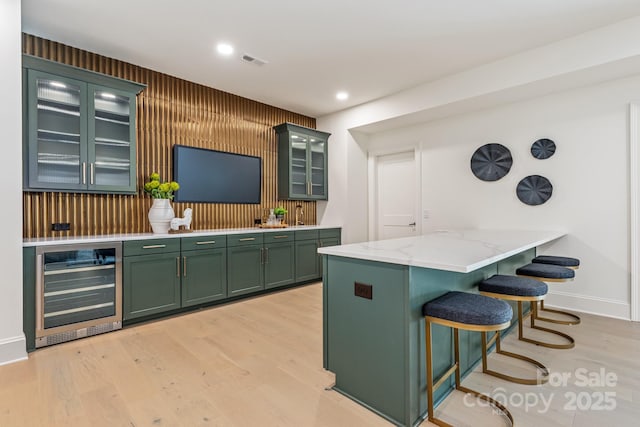 bar featuring beverage cooler, baseboards, visible vents, and light wood-style flooring