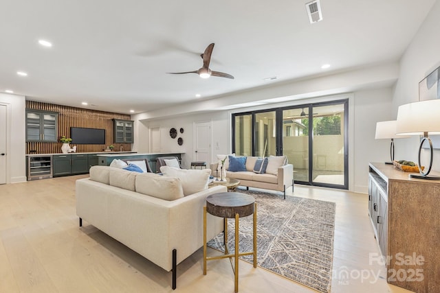 living area featuring beverage cooler, visible vents, recessed lighting, and light wood-style floors