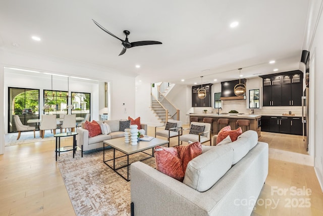 living room featuring ceiling fan, recessed lighting, light wood-style flooring, and stairs