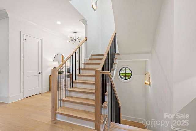 stairway with recessed lighting, baseboards, an inviting chandelier, and wood finished floors