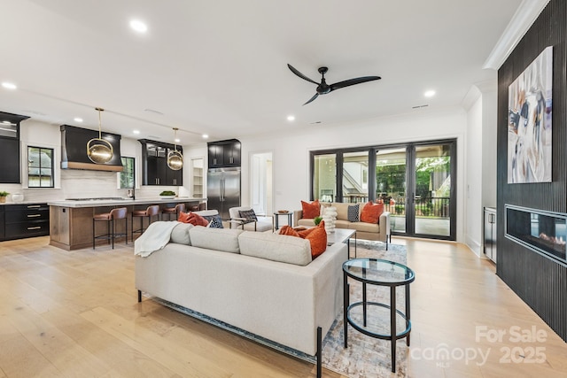 living area with light wood-style floors, crown molding, a ceiling fan, and recessed lighting