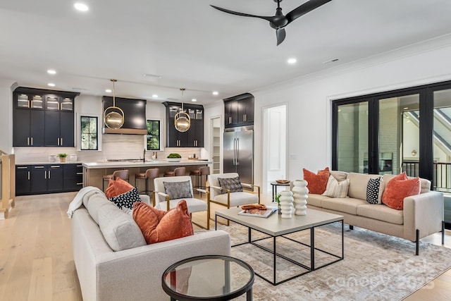 living room with crown molding, recessed lighting, light wood-style flooring, and a healthy amount of sunlight