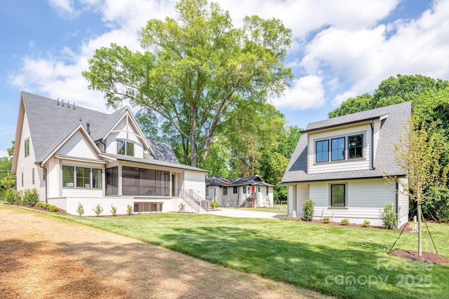 view of front of property featuring a front yard, a shingled roof, central AC unit, and a sunroom