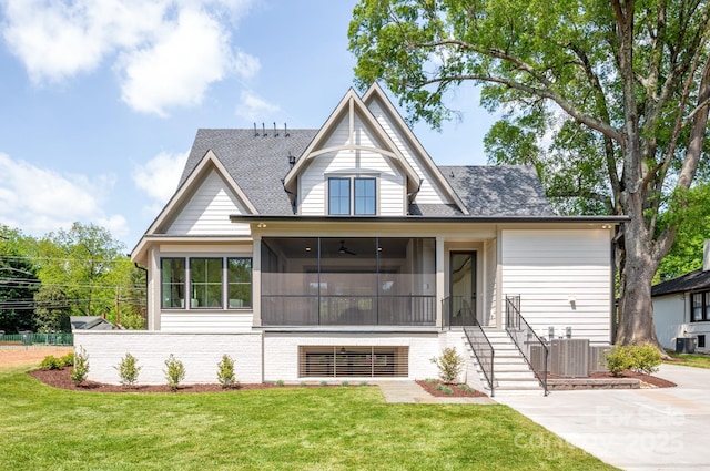 view of front of house with a sunroom, a front lawn, roof with shingles, and central air condition unit