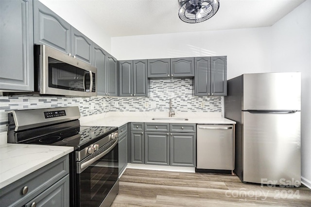 kitchen featuring gray cabinetry, decorative backsplash, sink, and stainless steel appliances