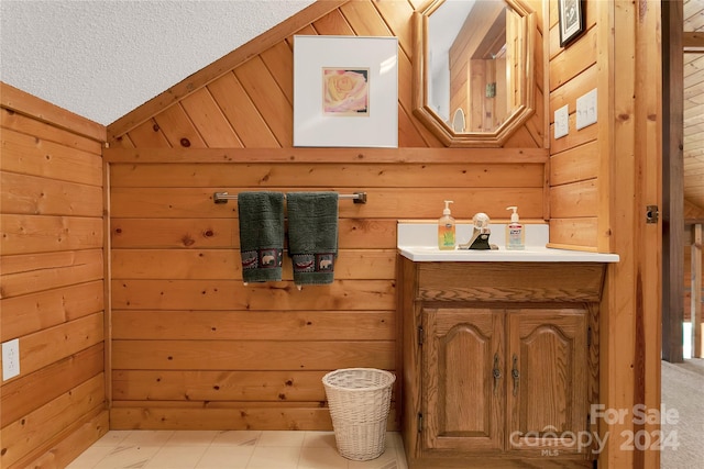 bathroom featuring lofted ceiling, a textured ceiling, wood walls, vanity, and tile patterned floors