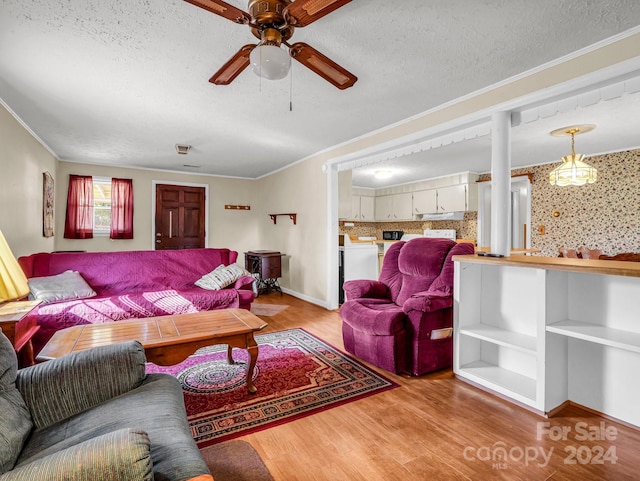 living room with ceiling fan, light hardwood / wood-style flooring, a textured ceiling, washer and clothes dryer, and ornamental molding