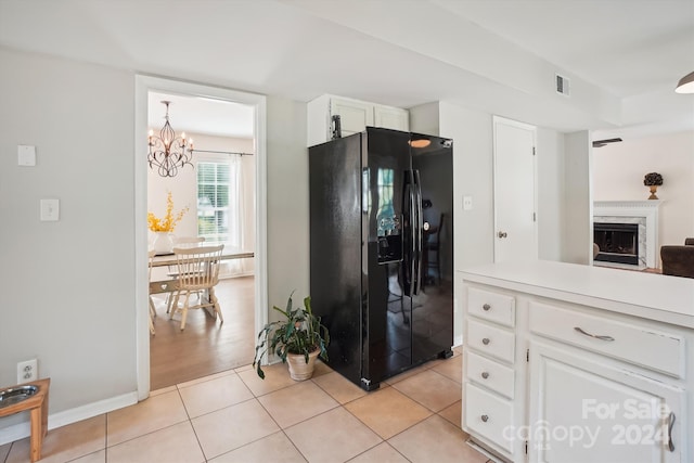 kitchen featuring light wood-type flooring, white cabinets, a premium fireplace, an inviting chandelier, and black refrigerator with ice dispenser