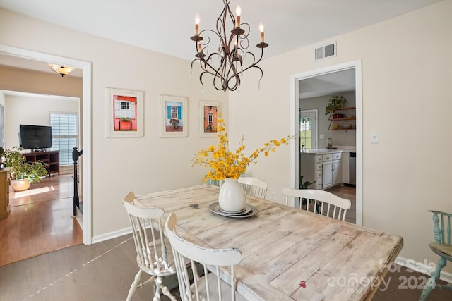 dining space with wood-type flooring and an inviting chandelier