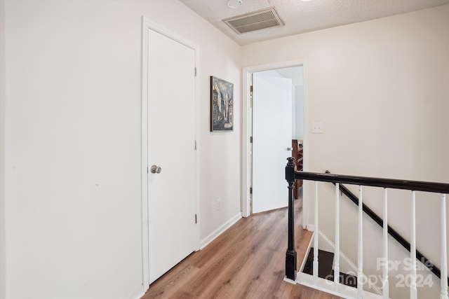 hall featuring a textured ceiling and light hardwood / wood-style flooring