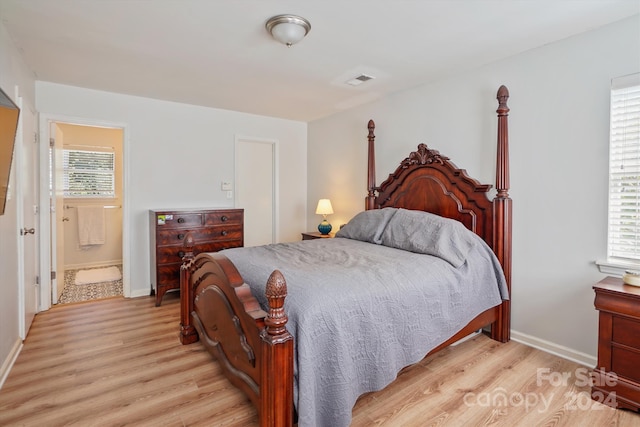 bedroom featuring light wood-type flooring and ensuite bath