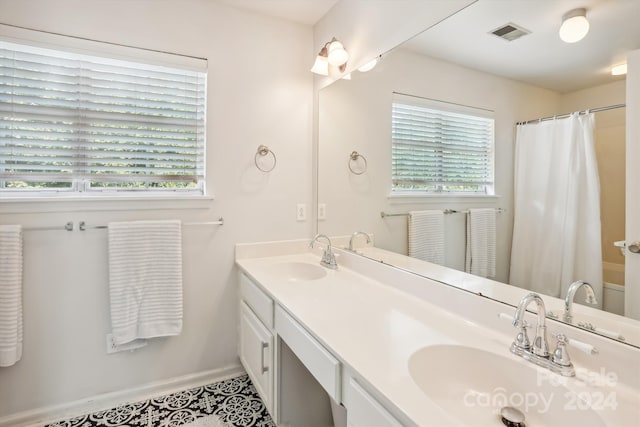 bathroom with a wealth of natural light, tile patterned flooring, walk in shower, and vanity