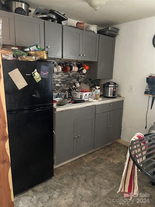 kitchen with black refrigerator, backsplash, and gray cabinetry