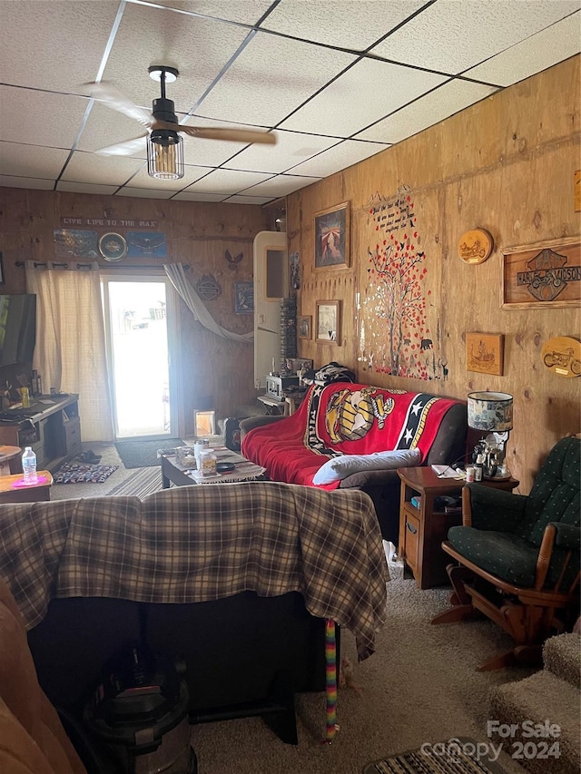 bedroom with ceiling fan, carpet, a drop ceiling, and wood walls