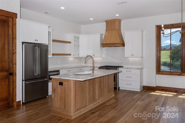 kitchen featuring premium appliances, white cabinetry, an island with sink, premium range hood, and sink