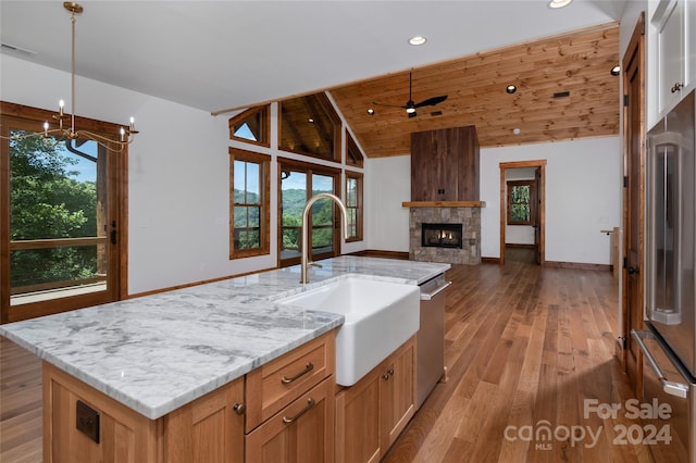 kitchen featuring a wealth of natural light, wood ceiling, stainless steel appliances, sink, and a kitchen island with sink