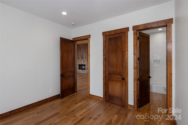 unfurnished bedroom with ensuite bathroom and light hardwood / wood-style flooring