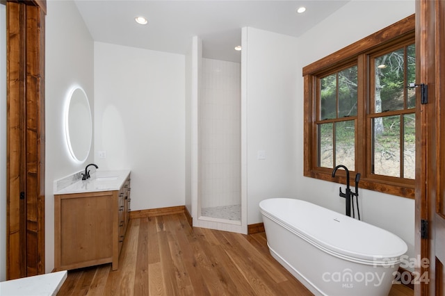 bathroom with wood-type flooring, vanity, and shower with separate bathtub