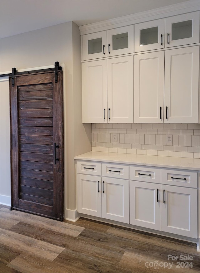 kitchen with white cabinets, dark wood-type flooring, tasteful backsplash, and a barn door