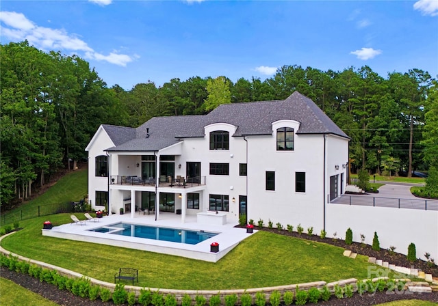 rear view of house featuring a fenced in pool, a lawn, a balcony, and a patio area