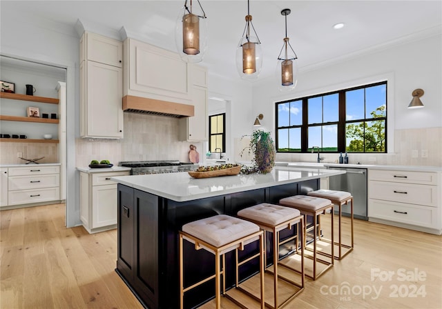 kitchen featuring a breakfast bar area, white cabinetry, hanging light fixtures, a kitchen island, and stainless steel dishwasher