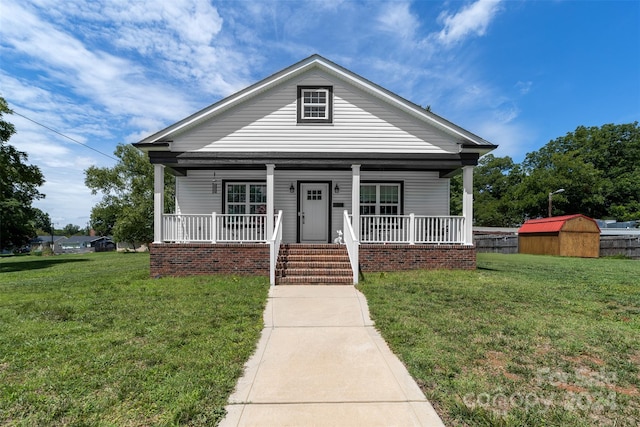 view of front of home featuring covered porch, a front lawn, and a shed