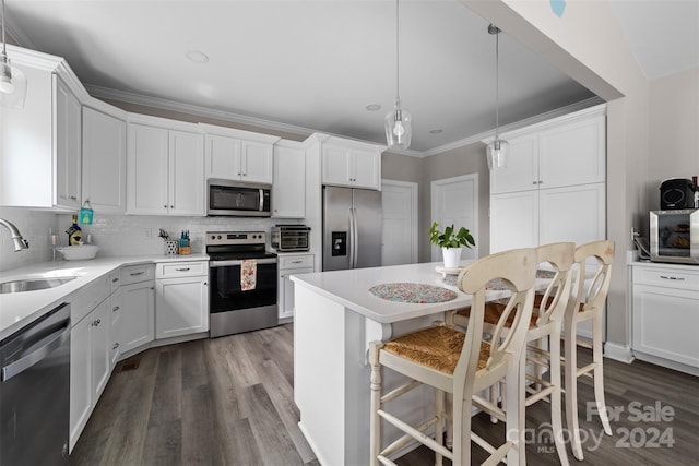 kitchen featuring appliances with stainless steel finishes, hardwood / wood-style floors, sink, hanging light fixtures, and backsplash