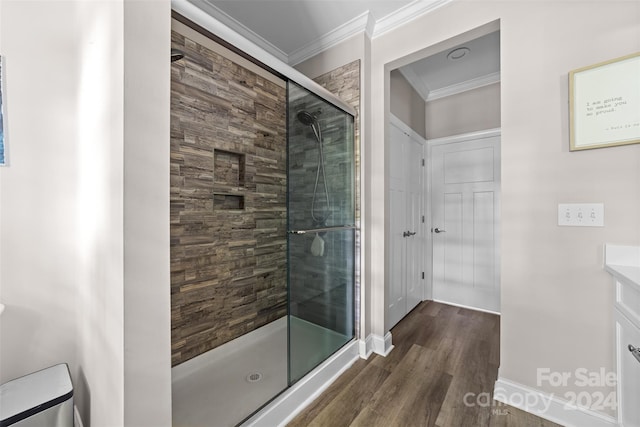 bathroom with wood-type flooring, a shower with shower door, vanity, and ornamental molding