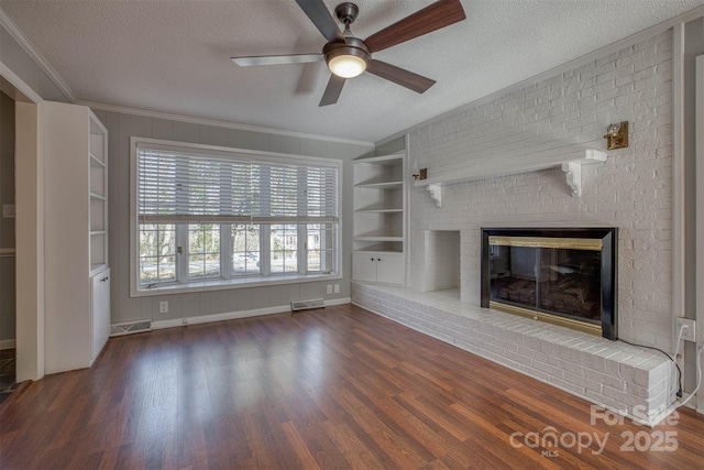 unfurnished living room with dark hardwood / wood-style flooring, a brick fireplace, built in features, and a textured ceiling