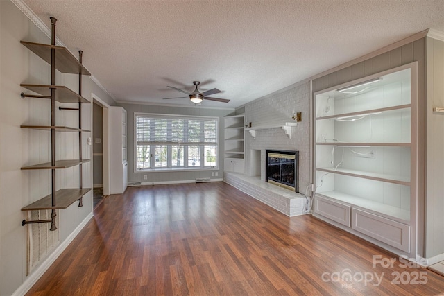 unfurnished living room featuring a fireplace, dark hardwood / wood-style flooring, built in features, and a textured ceiling